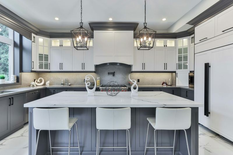 A white kitchen with a gray island and lantern pendants