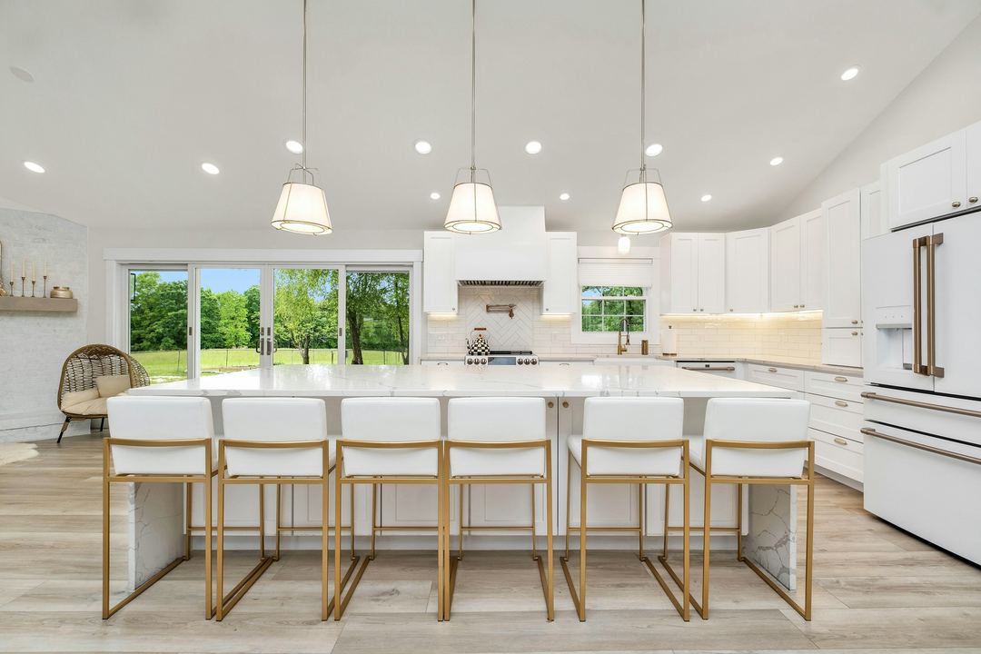 A bright white kitchen with an island and stools